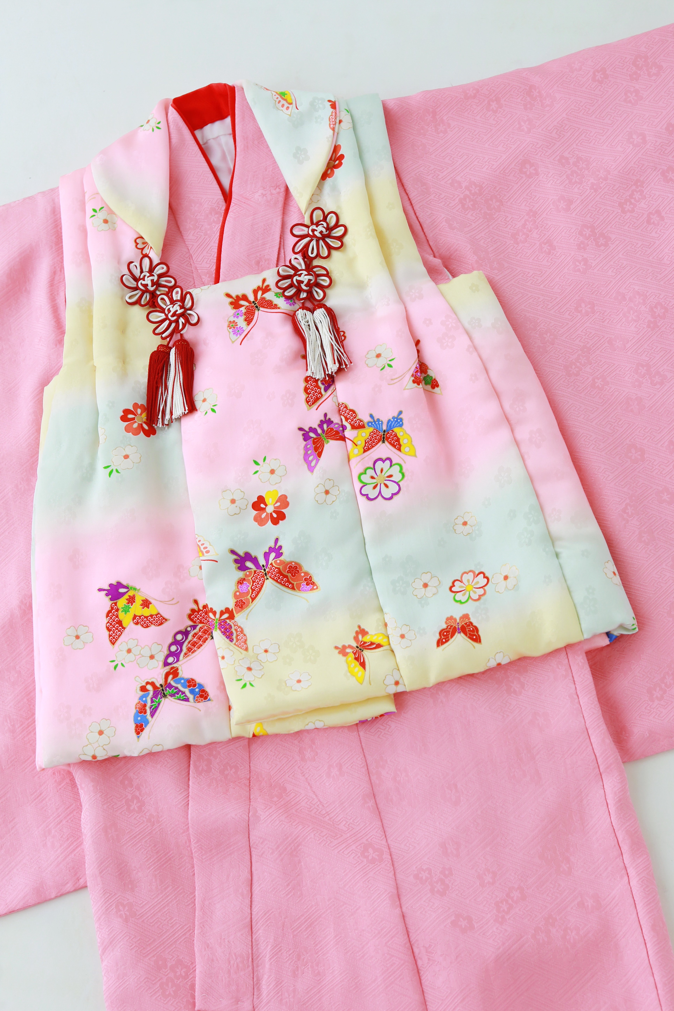 ピンクのお着物と蝶々柄の被布の組み合わせが、柔らかい色味で統一されたお着物です。