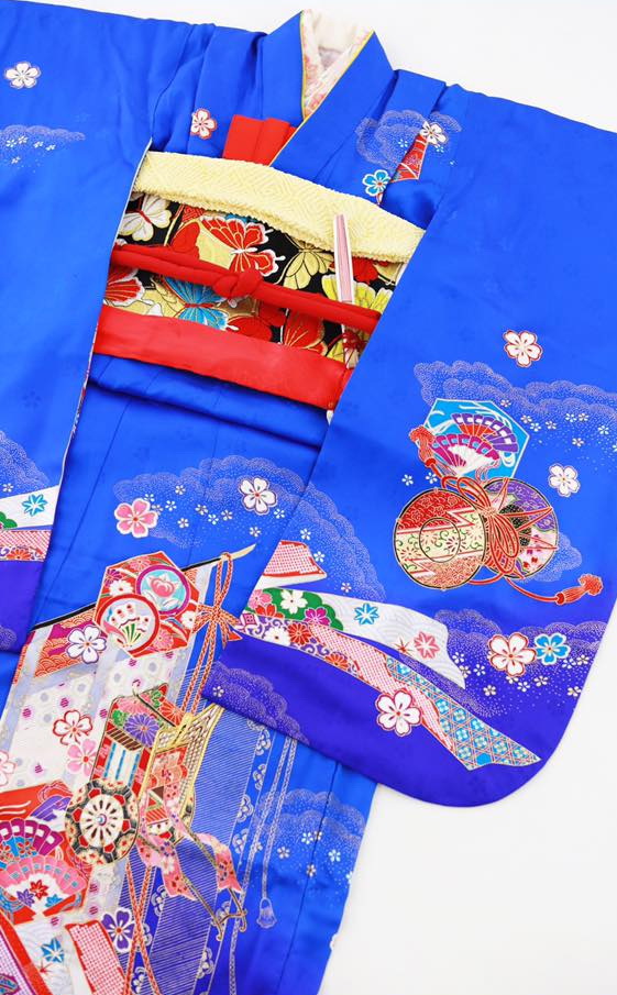 お着物の裾や振袖に、鼓・御所車・桜・亀甲文などのお祝いの模様が描かれている、とても華やかなお着物です。